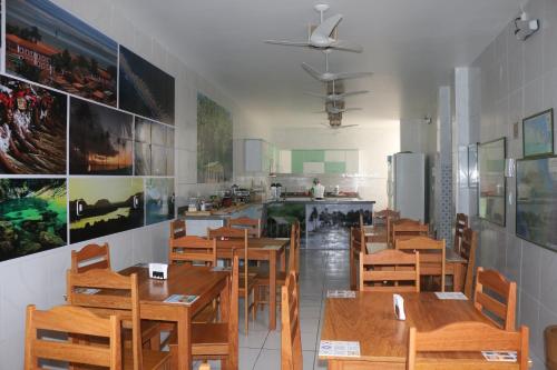 a restaurant with wooden tables and chairs and a kitchen at Pousada Maramazon in São Luís