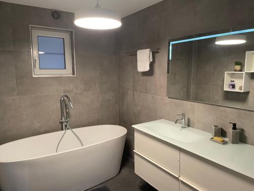een badkamer met een bad, 2 wastafels en een spiegel bij Guest House en famille ou en couple à la campagne in Romsée