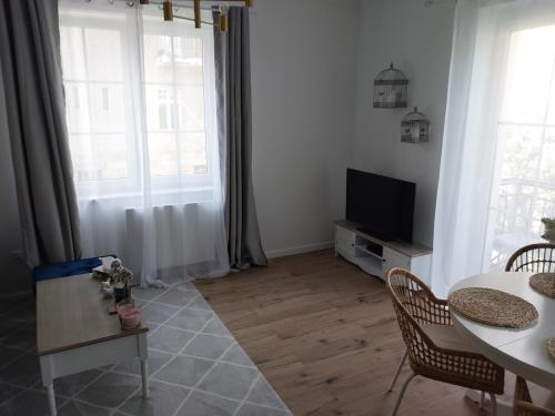 a living room with a table and a tv at APARTAMENT PIASTOWSKI in Polanica-Zdrój