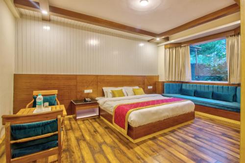a bedroom with a bed and a blue couch at Baan by Snow City Farm in Vashisht