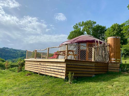 un grand bâtiment en bois dans un champ d'herbe dans l'établissement Yourte 2-4 personnes avec SPA, à Saint-Laurent-de-Lévézou