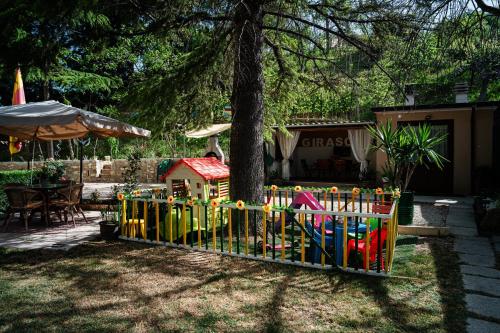 a fence with a play set in front of a tree at Il Girasole in Basciano