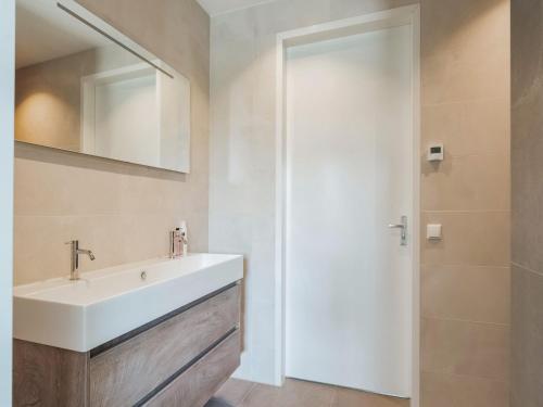 een badkamer met een wastafel en een spiegel bij Swanky villa in Zeewolde with garden in Zeewolde