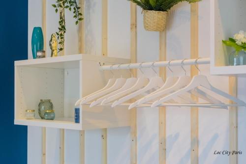 a shelf with white hangers on a wall at Studio Bleu - Parc Astérix - Mer de Sable - Villepinte - Aéroport CDG in Vémars