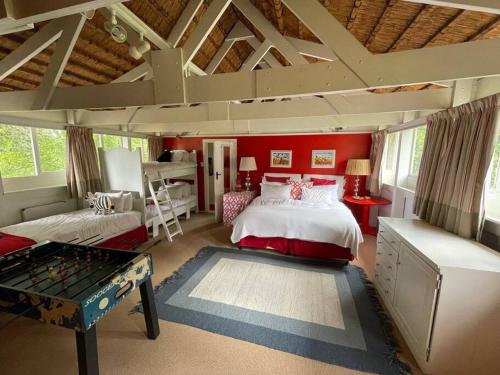 a bedroom with red walls and a bed and a table at Spring Close Boutique Cottage Nottingham Road in Nottingham Road
