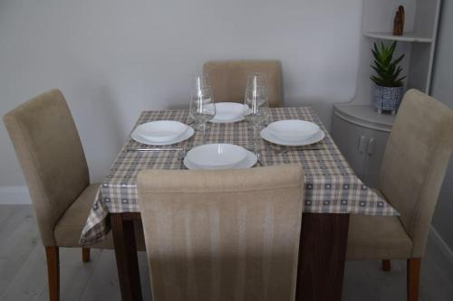 a table with four chairs and plates on it at 2 bed Apartment Ballycastle Seconds to Seafront in Ballycastle