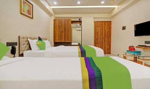 a bedroom with two beds and a flat screen tv at Treebo Royal Imperio, Hinjewadi in Pune
