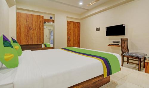 a bedroom with a bed and a chair and a television at Treebo Royal Imperio, Hinjewadi in Pune