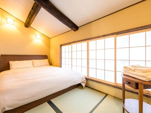 a bedroom with a bed and a large window at 慶有魚·東山(Kyotofish·Higashiyama)*景区核心町屋*地暖赏庭浴缸*京都民宿认证 in Kyoto