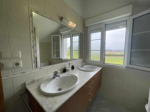 uma casa de banho com 2 lavatórios e um espelho grande em Grupo Gontad Casa Beo Malpica de Bergantiños em La Coruña