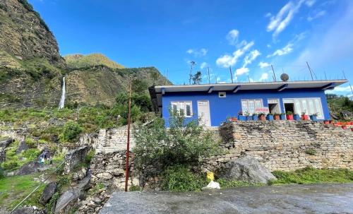 a blue house on the side of a mountain at Green Mountain Homestay - Birthi Falls near Munsyari in Munsyari