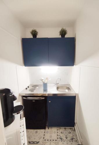 Elle comprend une petite cuisine avec un évier et des placards bleus. dans l'établissement Superbe studio à deux pas de la gare de Chartres, à Chartres