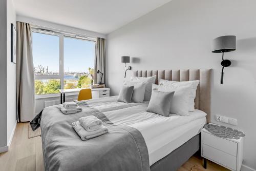 a white bedroom with a large bed with a window at Downtown Apartments Chlebova Riverside - Parking & Gym in Gdańsk