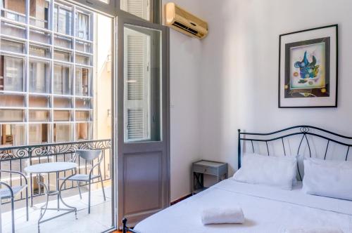 um quarto com uma cama e uma varanda com uma mesa em Dioskouros Hostel em Atenas