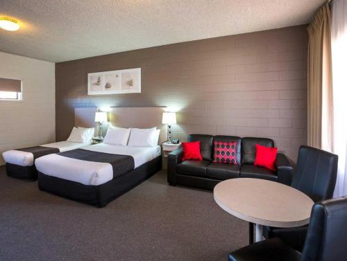 a hotel room with a bed and a couch and a table at Comfort Inn & Suites King Avenue in Sale