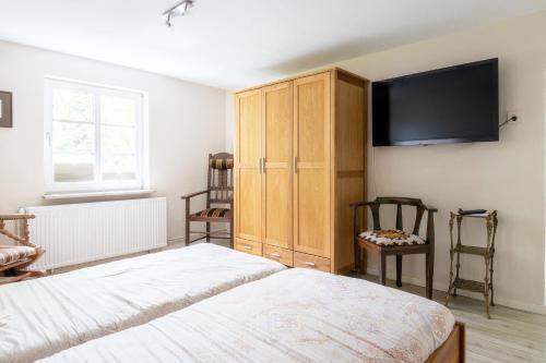 a bedroom with a bed and a cabinet and a tv at Landsitz Braderup Festland in Braderup