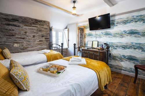 a hotel room with two beds with a tray of bread at The Olde Malthouse Inn in Tintagel