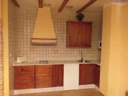 uma cozinha com armários de madeira e um lavatório em Apartamentos Cuesta de la Cruz em Caravaca de la Cruz