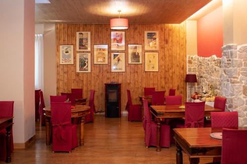 a restaurant with wooden tables and red chairs at Hotel Fiordigigli in Assergi