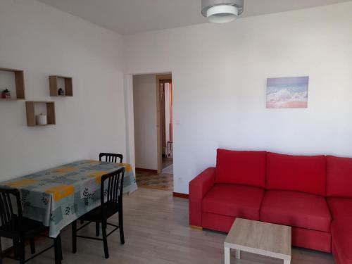 un salon avec un canapé rouge et une table dans l'établissement Appartement aux portes de l ardèche en cevennes, à Saint-Ambroix