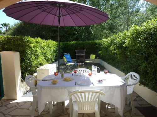 - une table avec un parasol violet sur la terrasse dans l'établissement Appartement en Rez-de-Jardin Proche Plage avec Terrasse et Confort Moderne - FR-1-387-54, à Marseillan