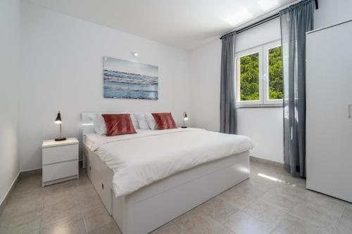 a white bedroom with a bed and a window at New Villa Zara with 32 sqm heated Pool, Jacuzzi, Billiard, Tennis table, 8pax in Kučiće