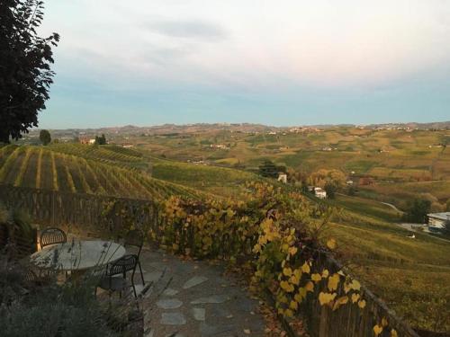 een tafel en bank op een heuvel met een wijngaard bij CANNUBI SAN LORENZO,Mansarda in Barolo