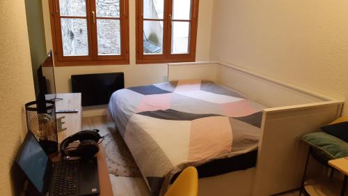 um quarto com uma cama e uma secretária com um computador portátil em Studio 202 au 15 rue Battant à Besançon em Besançon