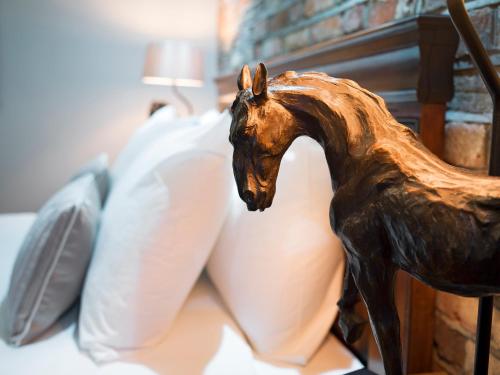 a wooden horse statue sitting on top of a bed at The Merchant's House, BW Signature Collection in Salisbury