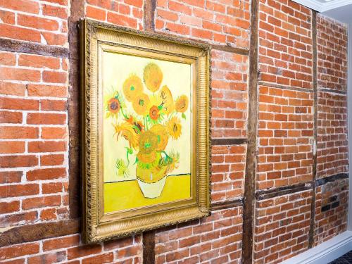 a painting of a vase of flowers on a brick wall at The Merchant's House, BW Signature Collection in Salisbury