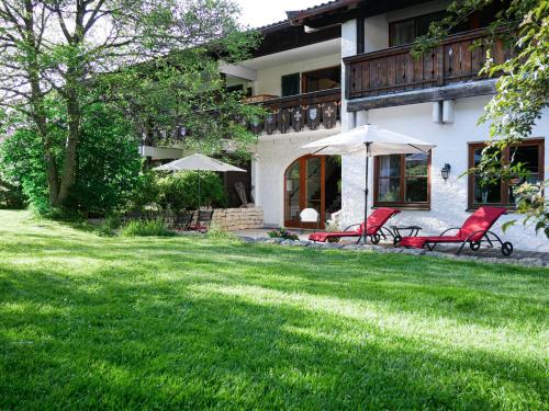 a house with two red chairs and an umbrella at Helles 2-Zimmer-Apartment in Ostin am Tegernsee in Gmund am Tegernsee