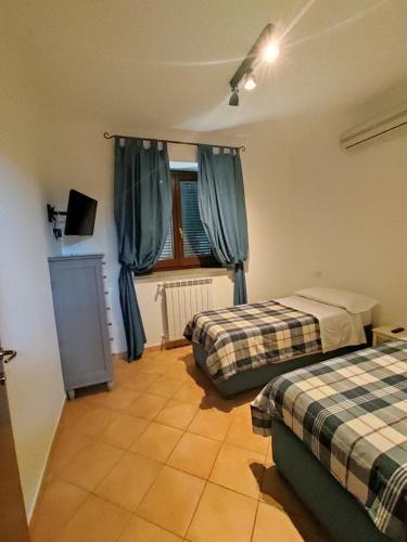 1 dormitorio con 2 camas y una ventana con cortinas azules en Agricampolungo Monterosi en Monterosi