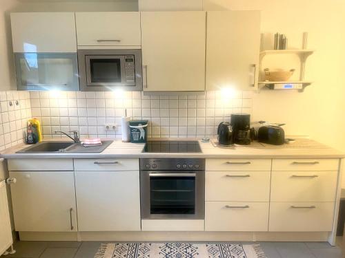a kitchen with white cabinets and a stove top oven at FeWo Lüttje Wooge Dornum in Dornum