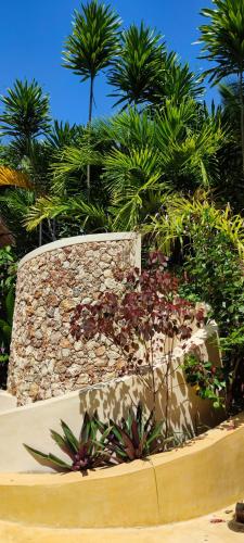 a garden with palm trees and a stone wall at Lions' Luxury Eco Resort & Spa in Malindi