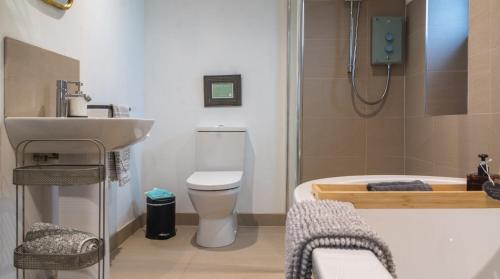 a bathroom with a tub and a toilet and a sink at Hillside Haven, panoramic views Nr Bakewell in Great Rowsley