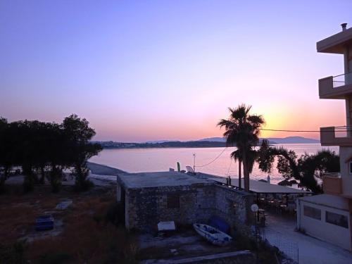 a sunset over the water with a building and a palm tree at THALIA APARTMENTS CHANlA in Chania Town