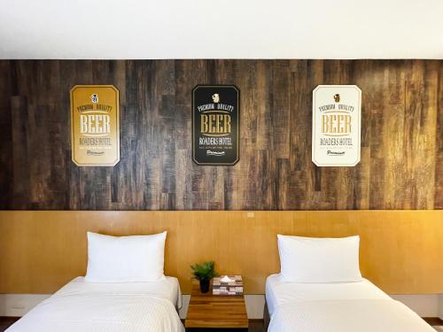 two beds in a room with a wall with beer signs at Roaders Hotel Hualien Dongda in Hualien City