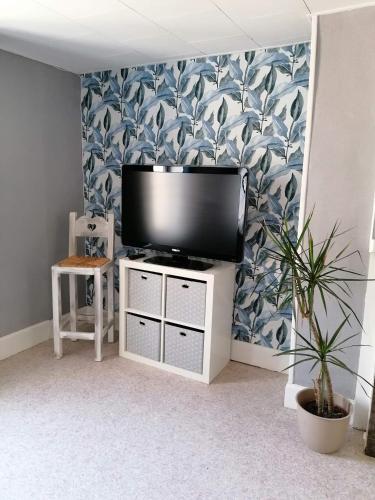 Elle comprend une télévision à écran plat installée au-dessus d'un meuble blanc. dans l'établissement studio de Charme hyper centre, à Boulogne-sur-Mer