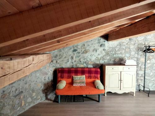 a couch in a room with a stone wall at Agroturismo Erlete Goikoa -ESTAMOS EN EL CAMINO DE SANTIAGO -WE ARE ON THE CAMINO DE SANTIAGO in Deba