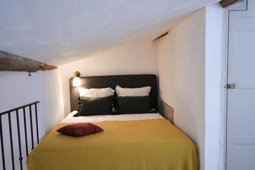 a small bedroom with a bed with a yellow blanket at La Cachette du Comte in Montfort-sur-Argens