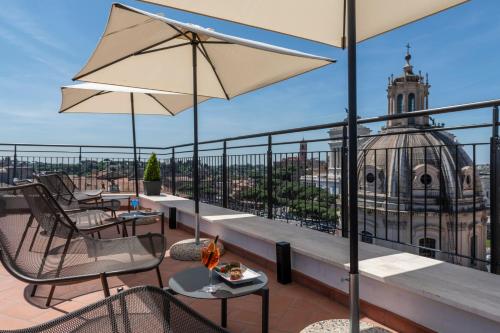 a balcony with chairs and tables with a view of a building at H10 Palazzo Galla in Rome