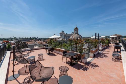 eine Terrasse mit Stühlen und Tischen auf dem Dach in der Unterkunft H10 Palazzo Galla in Rom