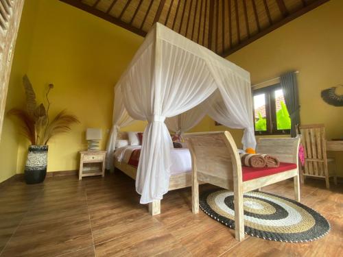um quarto com uma cama de dossel e uma cadeira em TAMAN EDEN COTTAGE em Ubud