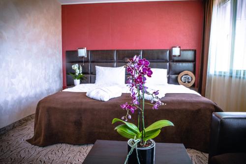a bedroom with a large bed with a red wall at Zdravets SPA Hotel in Velingrad