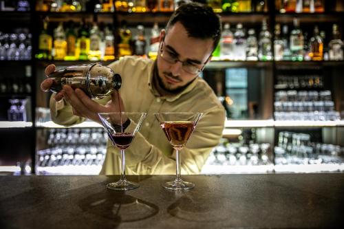 a man pouring wine into two glasses at a bar at Zdravets SPA Hotel in Velingrad