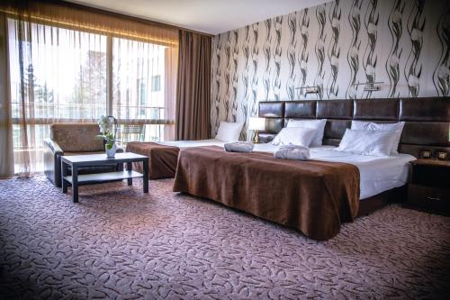a hotel room with two beds and a chair at Zdravets SPA Hotel in Velingrad