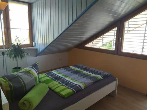 - un lit avec des oreillers verts dans une chambre avec des escaliers dans l'établissement Ferienwohnung Klaus, à Wolfegg