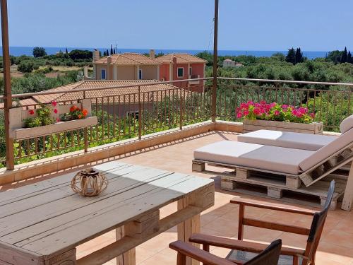 a patio with a wooden table and chairs and flowers at Anio Residence - Rustic Modern with Sea and Mountain View Terrace in Svoronata