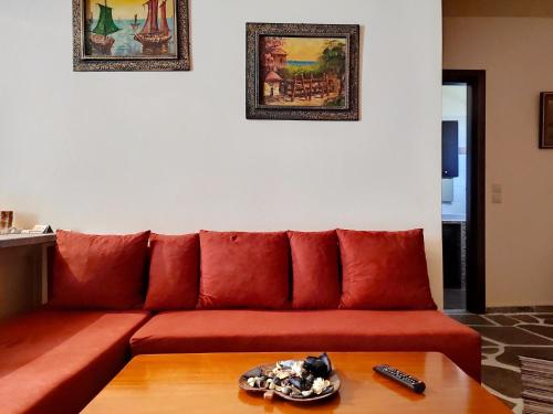 a red couch in a living room with a table at KERAMIDI GUESTHOUSE in Keramídhion