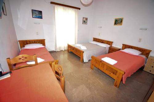 a room with three beds and tables and a window at Mega Apartments in Tiros